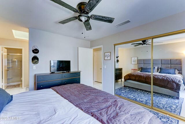 bedroom featuring a ceiling fan, visible vents, a closet, ensuite bath, and light tile patterned flooring