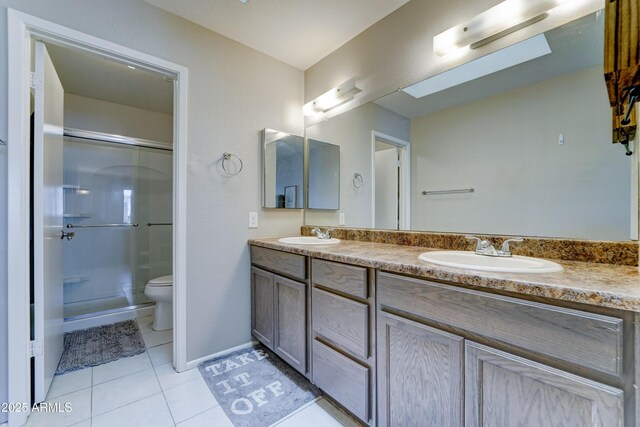 full bath with double vanity, tile patterned flooring, a shower with shower door, a sink, and toilet