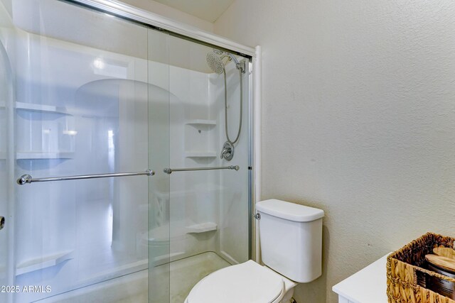 bathroom featuring toilet and a shower stall