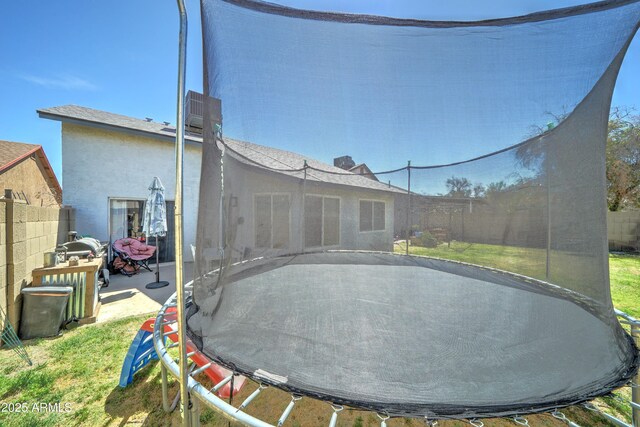 back of property featuring a fenced backyard, a trampoline, a patio area, and a yard