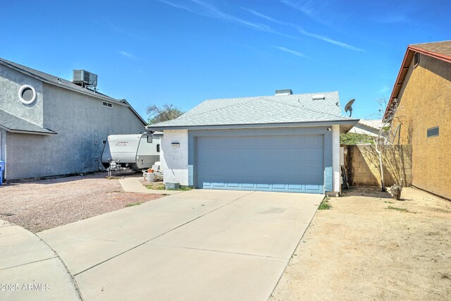 exterior space featuring fence, a shingled roof, a garage, stucco siding, and concrete driveway