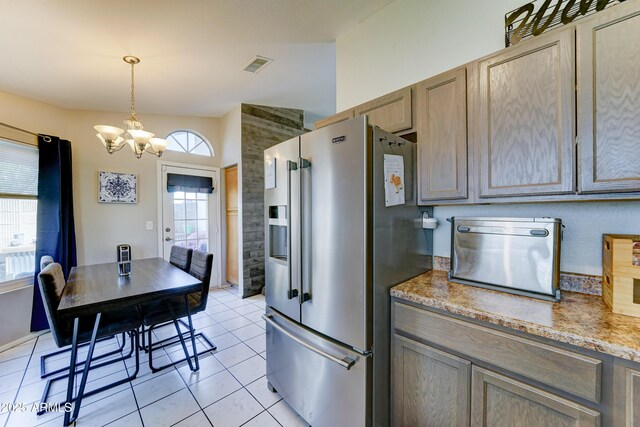 kitchen with a notable chandelier, light tile patterned floors, stainless steel refrigerator with ice dispenser, visible vents, and pendant lighting