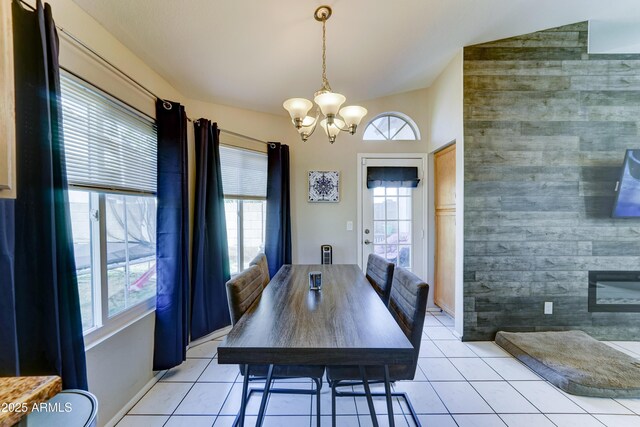 dining space with an inviting chandelier, light tile patterned flooring, lofted ceiling, and a healthy amount of sunlight
