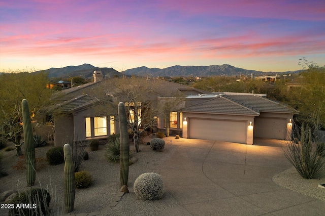 view of front of house featuring a tiled roof, stucco siding, driveway, a garage, and a mountain view