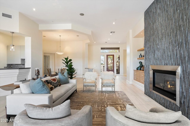 living area featuring visible vents, recessed lighting, and a glass covered fireplace