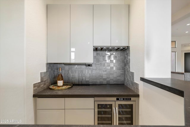 kitchen with beverage cooler, white cabinets, tasteful backsplash, and dark countertops