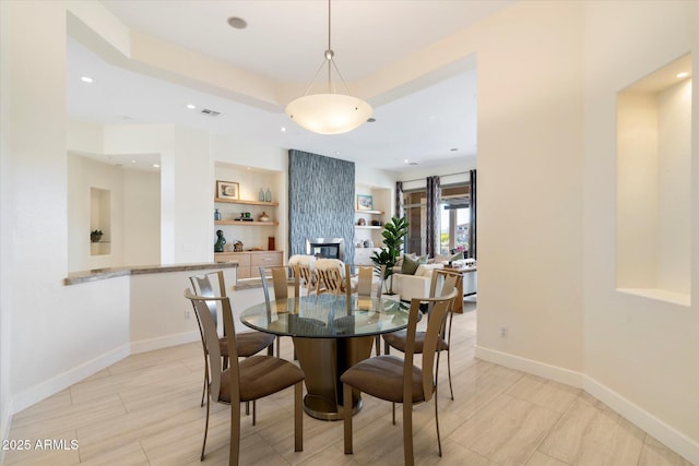 dining room with visible vents, a tray ceiling, recessed lighting, a large fireplace, and baseboards