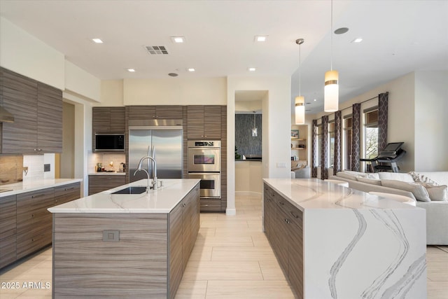 kitchen with a large island, built in appliances, modern cabinets, and visible vents