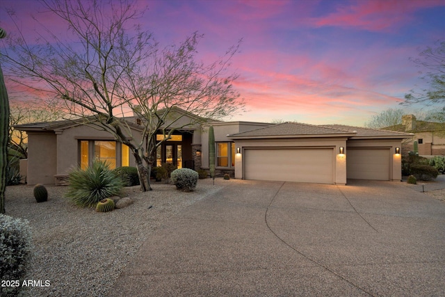 view of front of home featuring a tile roof, a garage, driveway, and stucco siding