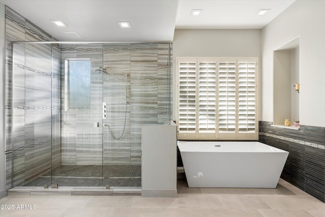 bathroom featuring a freestanding tub, tile walls, and a stall shower