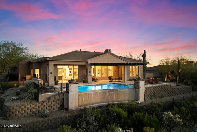 rear view of house featuring a patio area, fence, a fenced in pool, and stucco siding