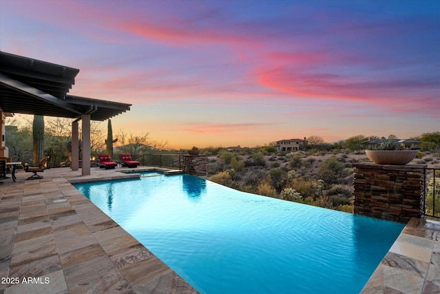 view of swimming pool featuring an infinity pool, a patio, and fence