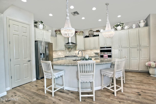 kitchen with light hardwood / wood-style flooring, stainless steel appliances, a chandelier, and a kitchen island with sink