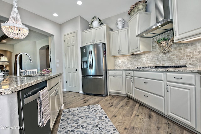 kitchen featuring white cabinets, stainless steel appliances, wall chimney exhaust hood, and sink