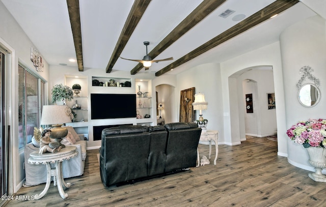 living room featuring dark wood-type flooring, built in features, ceiling fan, and beamed ceiling