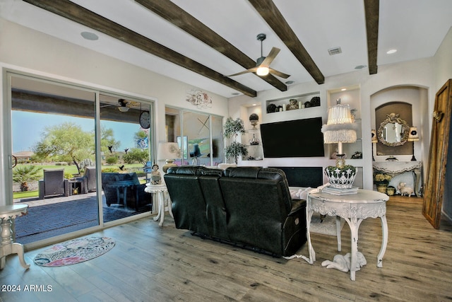 living room featuring beamed ceiling, wood-type flooring, built in features, and ceiling fan