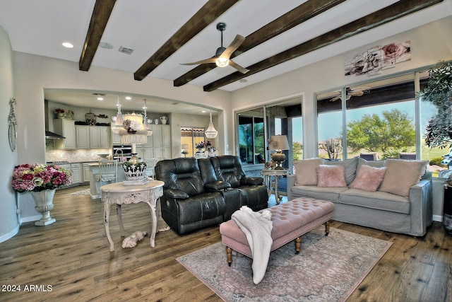 living room with a wealth of natural light, dark hardwood / wood-style floors, ceiling fan with notable chandelier, and beamed ceiling