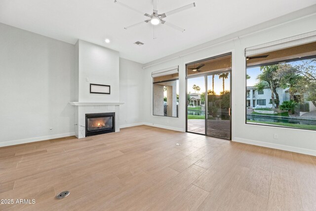 1724 W Blue Ridge Way, Chandler, AZ 85248 - unfurnished living room with ceiling fan, a glass covered fireplace, light wood finished floors, and baseboards
