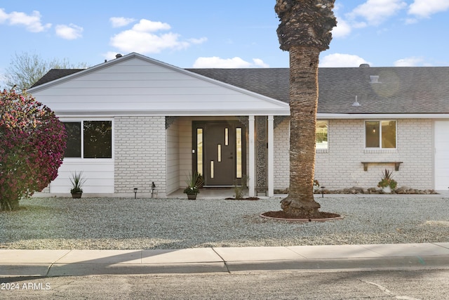 view of front of home with roof with shingles and brick siding