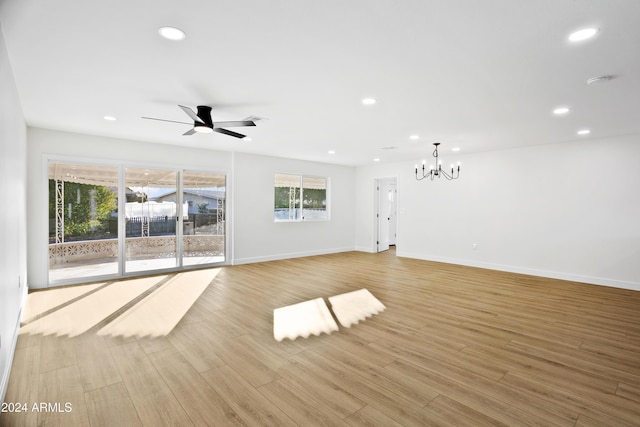 unfurnished living room with light wood-type flooring, ceiling fan with notable chandelier, baseboards, and recessed lighting