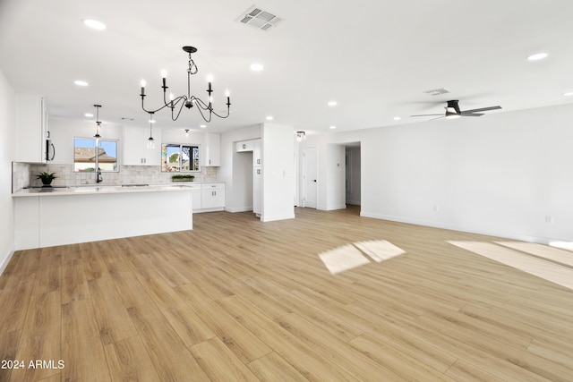 unfurnished living room featuring recessed lighting, visible vents, light wood-style flooring, and ceiling fan with notable chandelier