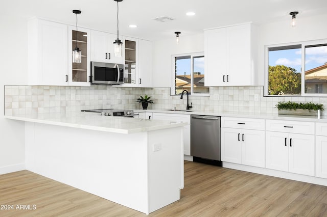 kitchen featuring white cabinetry, glass insert cabinets, stainless steel appliances, and light countertops