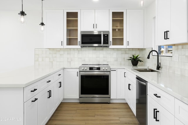 kitchen featuring stainless steel appliances, hanging light fixtures, glass insert cabinets, white cabinets, and a sink