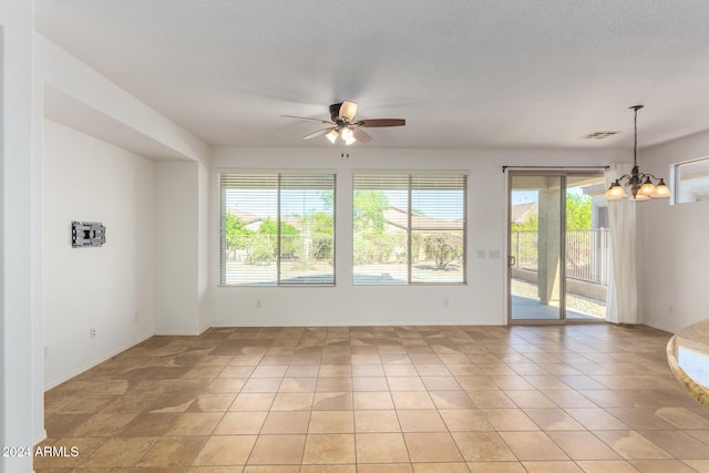 spare room featuring a textured ceiling, ceiling fan with notable chandelier, and light tile patterned floors