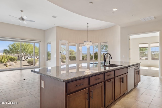 kitchen with plenty of natural light, a center island with sink, sink, and stone counters