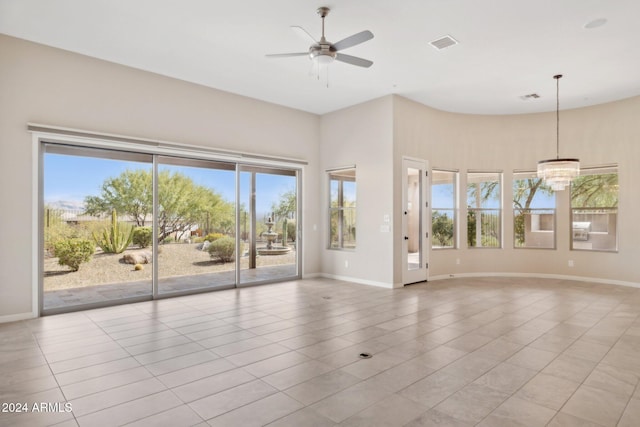 unfurnished living room with a towering ceiling, ceiling fan with notable chandelier, and light tile patterned floors