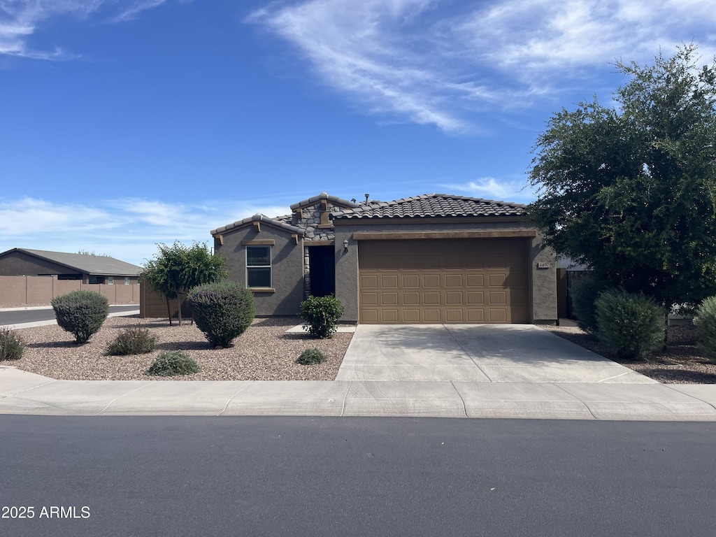 view of front facade with driveway, fence, a tiled roof, an attached garage, and stucco siding
