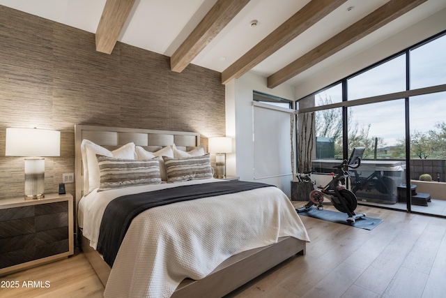 bedroom with beam ceiling, light hardwood / wood-style flooring, a high ceiling, and access to outside