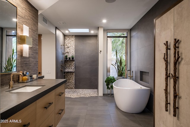 bathroom featuring tile walls, a skylight, vanity, tile patterned floors, and separate shower and tub