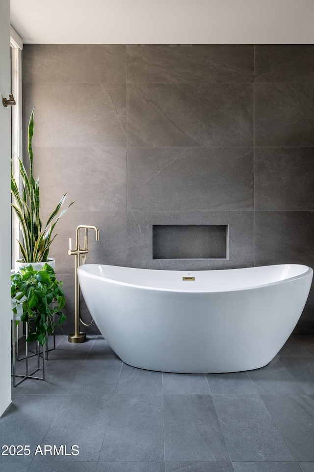 bathroom featuring a bath and tile walls