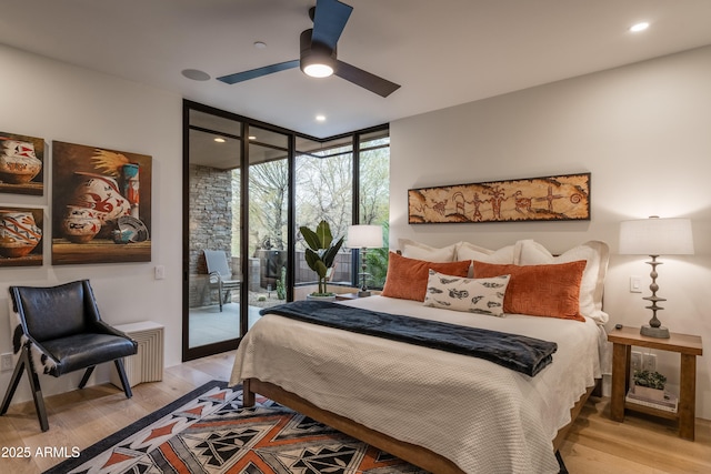 bedroom featuring light hardwood / wood-style flooring, access to outside, expansive windows, and ceiling fan