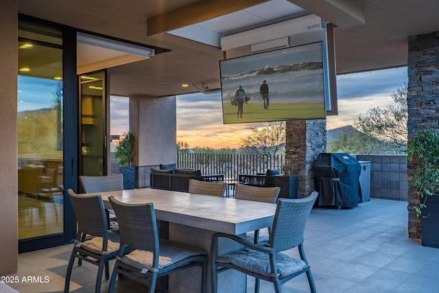 patio terrace at dusk featuring a grill