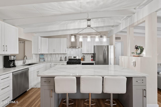 5833 N 10th St, Phoenix, AZ 85014 - kitchen with appliances with stainless steel finishes, wall chimney exhaust hood, a breakfast bar area, beamed ceiling, and dark wood-style flooring