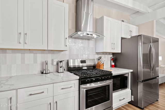 5833 N 10th St, Phoenix, AZ 85014 - kitchen featuring stainless steel appliances, wall chimney range hood, light wood-type flooring, white cabinets, and light stone countertops