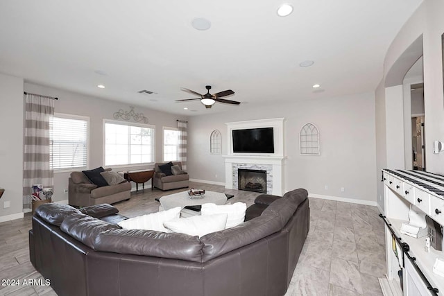 living room with ceiling fan and a stone fireplace