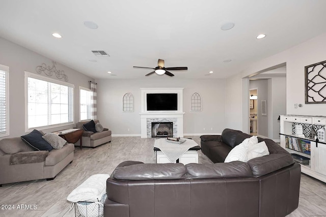 living room with ceiling fan and a fireplace