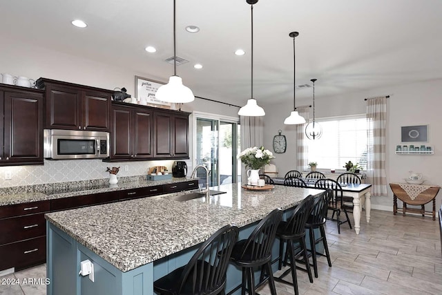 kitchen with dark brown cabinets, hanging light fixtures, and sink