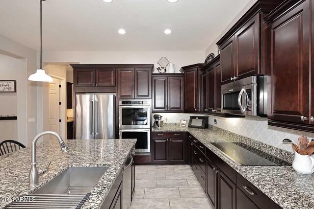 kitchen with tasteful backsplash, stainless steel appliances, sink, pendant lighting, and stone countertops