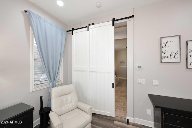 sitting room with a barn door and hardwood / wood-style floors