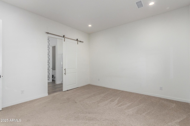 unfurnished room featuring carpet flooring and a barn door