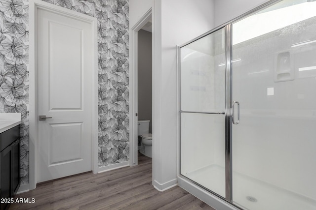 bathroom with vanity, hardwood / wood-style flooring, a shower with door, and toilet