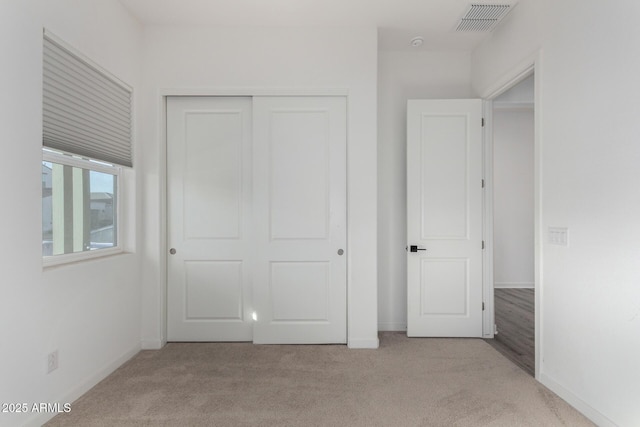 unfurnished bedroom featuring light colored carpet and a closet