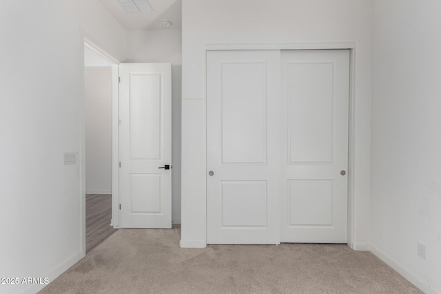 unfurnished bedroom featuring light carpet and a closet