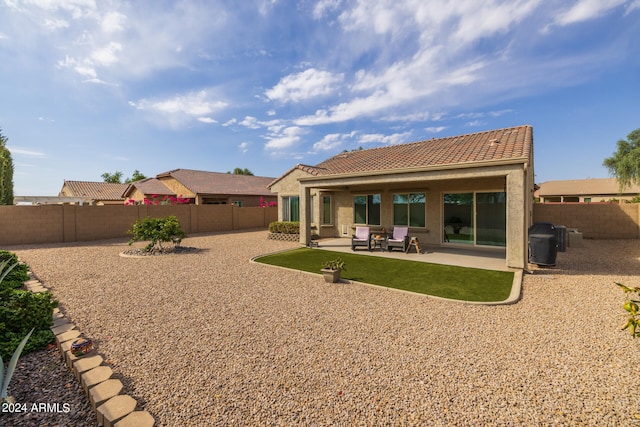 rear view of property with a tiled roof, a patio area, a fenced backyard, and stucco siding