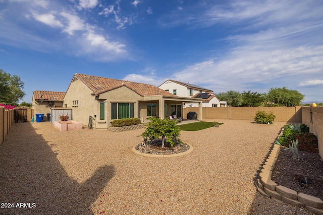 rear view of property with a fenced backyard, a patio area, a tiled roof, and stucco siding