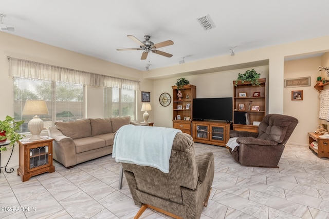 living room with a wealth of natural light, marble finish floor, visible vents, and ceiling fan